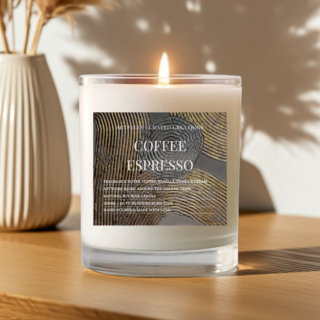 A lit scented candle in a clear glass jar sits on a wooden surface. The candle has white wax and a front label reading 'COFFEE ESPRESSO' with a dark wood-grain pattern.