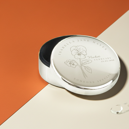 Silver compact mirror with floral design on an orange and beige background