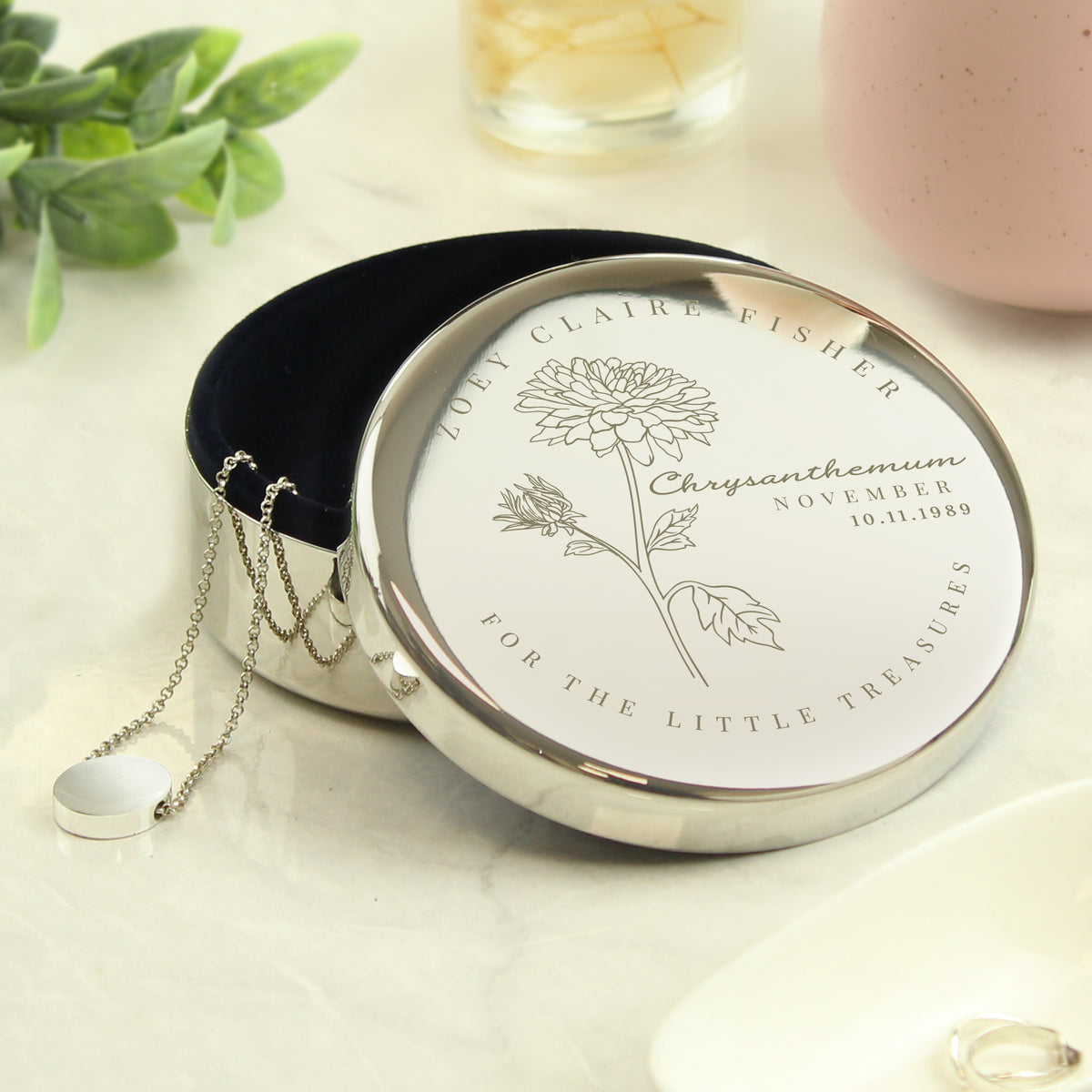 Silver necklace in a decorative box with floral design and text