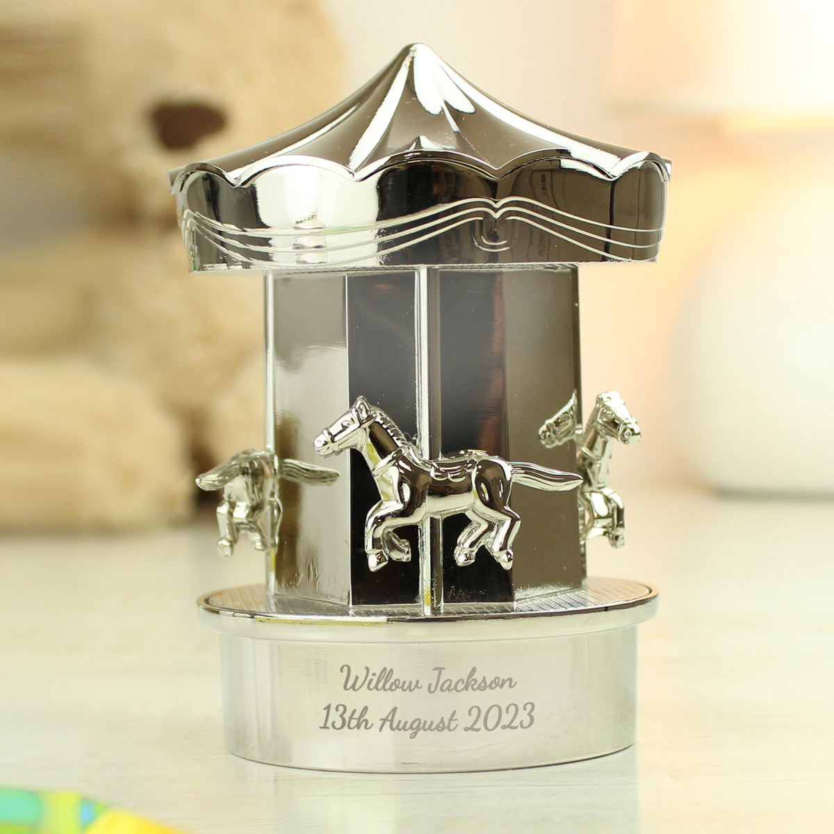 Silver carousel figurine with engraved text on a blurred background