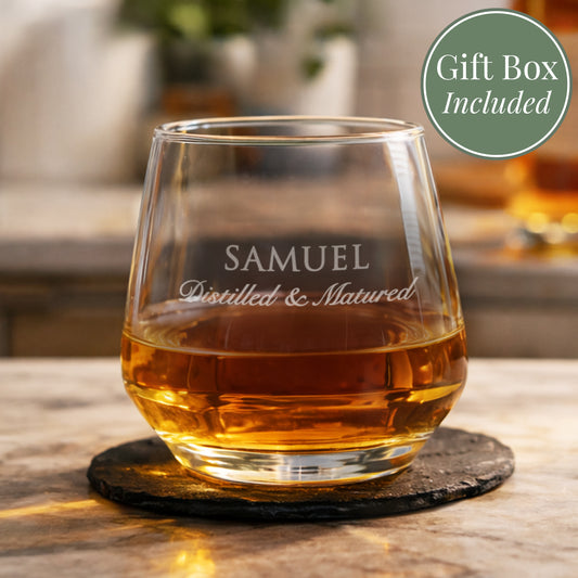 Glass of whiskey with 'SAMUEL Distilled & Matured' text on a wooden table, gift box included.