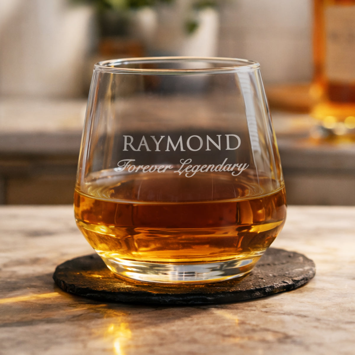 Glass of whiskey with 'RAYMOND Forever Legendary' engraving on a wooden surface.