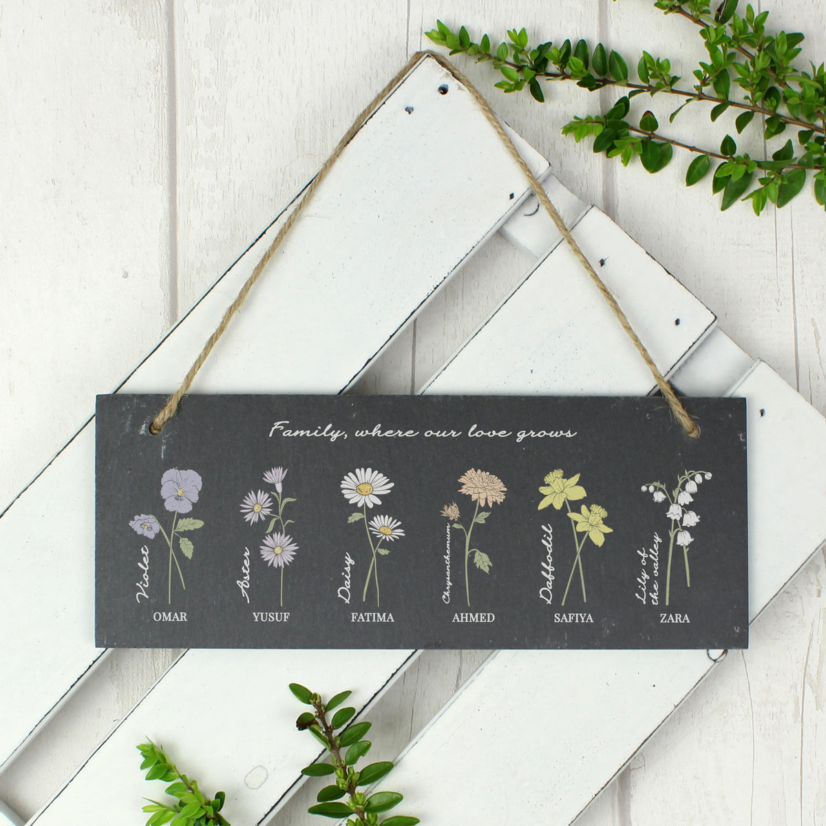 Decorative sign with floral illustrations and names on a wooden background