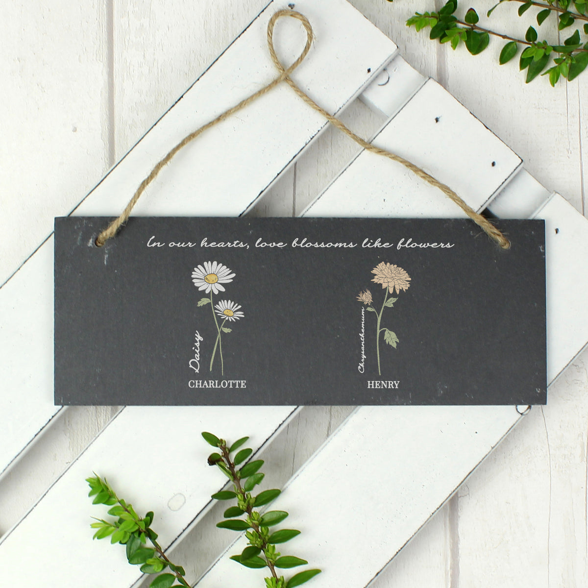 Decorative hanging sign with floral illustrations and text on a white wooden background