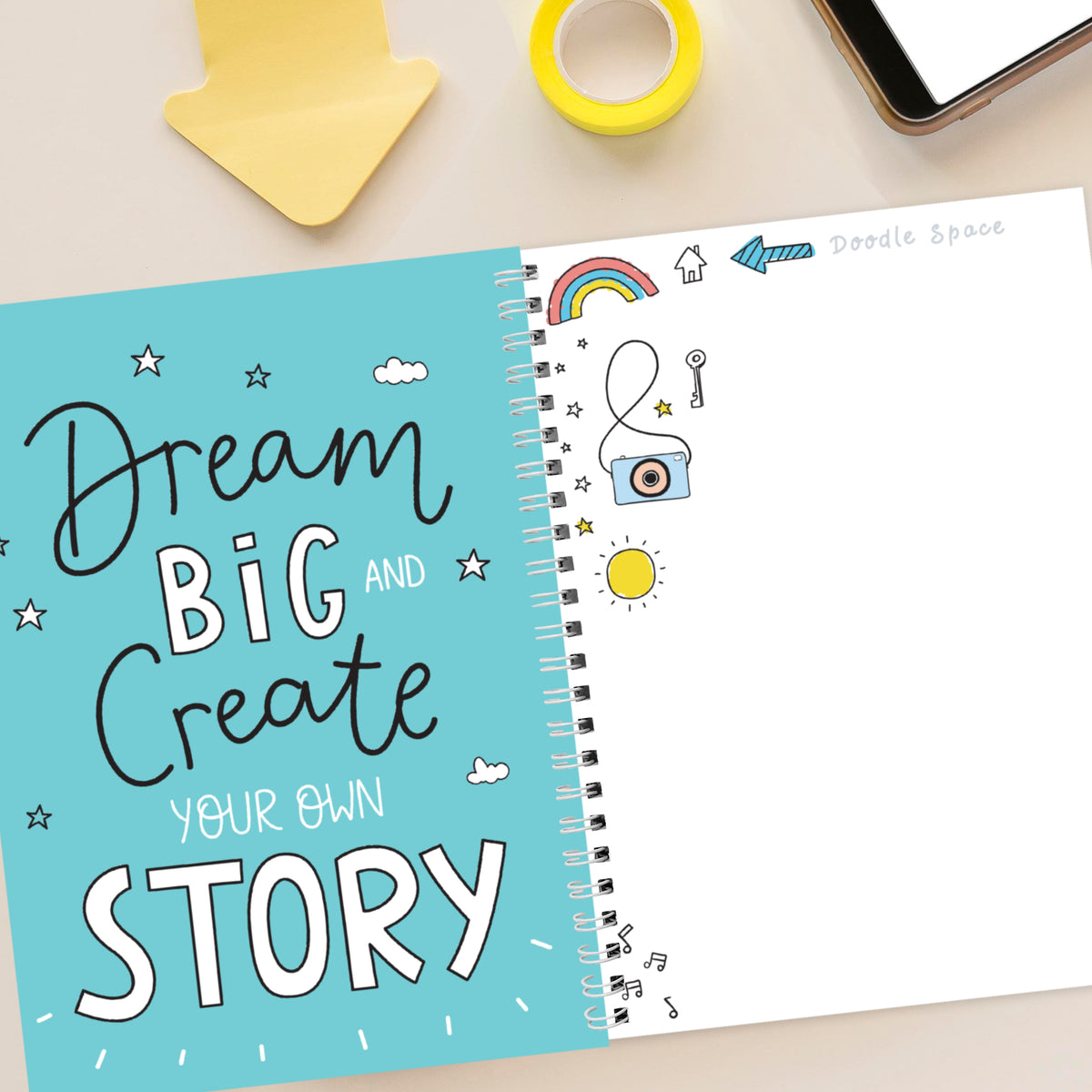 Notebook with 'Dream Big and Create Your Own Story' text on a light background