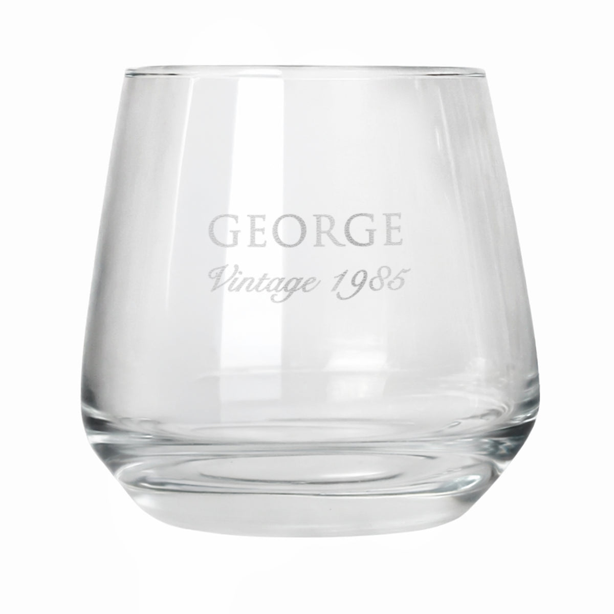 Clear glass tumbler with engraved text 'GEORGE Vintage 1985' on a white background