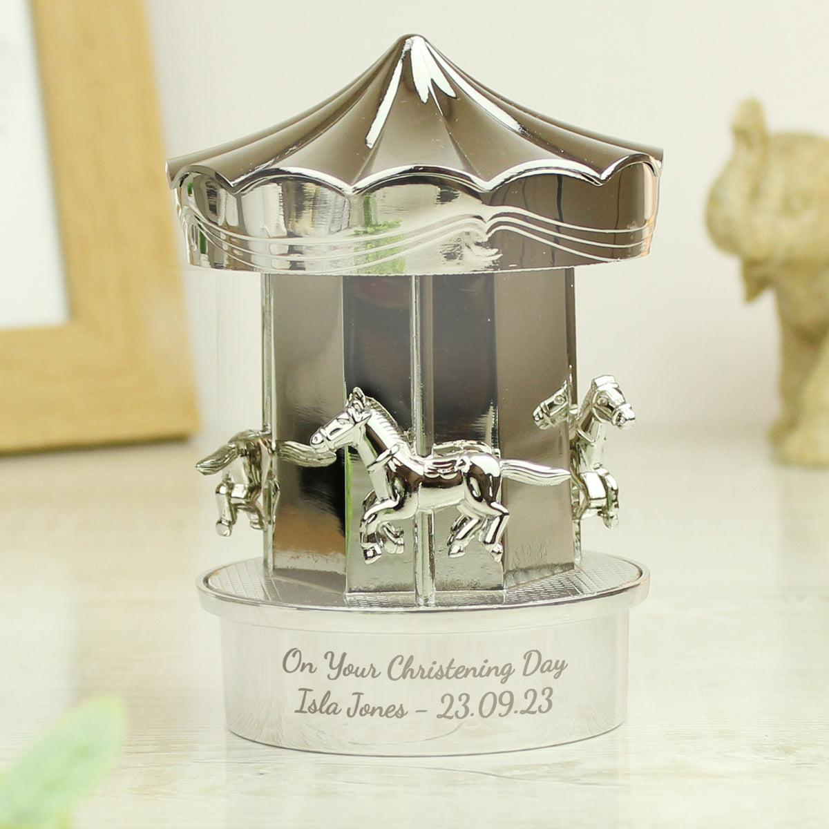 Decorative silver carousel figurine with engraved text on a light background